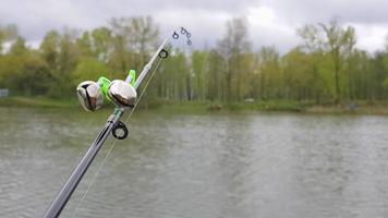 les cloches de pêche en argent sont portées sur une canne à pêche pendant la pêche. signal d'appel de morsure, à l'extrémité de la tige. une alarme de morsure vous avertira d'une morsure. gros plan de matériel de pêche. video