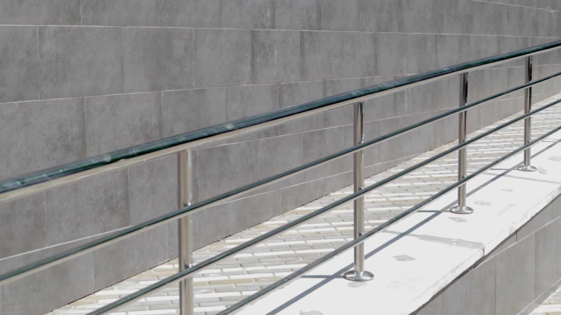 A ramp with stainless steel handrails for wheelchairs, bicycles and