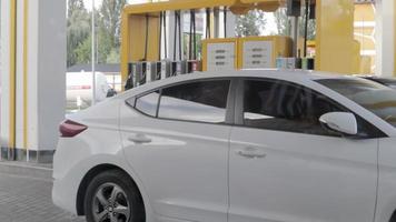 un hombre llena un auto en una gasolinera. el concepto de petróleo y precios de gasolina, combustible, gas. proceso de reabastecimiento de combustible del automóvil. la bomba de combustible se usa en una gasolinera. ucrania, Kyiv - 7 de agosto de 2021. video
