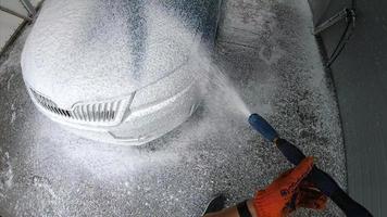 Young man covered soap suds on his car photo