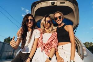 Three young woman posing for the camera the car park. photo