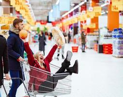 Young handsome guy rides a girl in a supermarket in a trolley photo