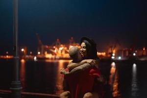 chico y chica abrazándose en un fondo del puerto nocturno foto
