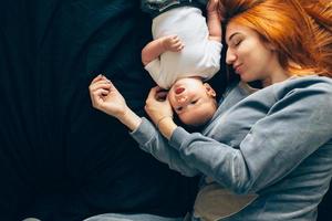 feliz madre con bebé acostado juntos en la cama foto