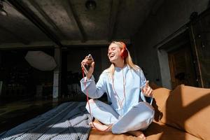 Natural smiling blonde listening to music in bedroom photo