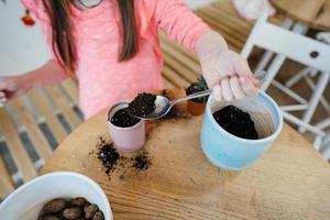 Little girl digs up the ground for rosetting with a spoon photo