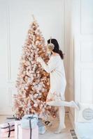 Young woman in an elegant dress near the Christmas tree photo