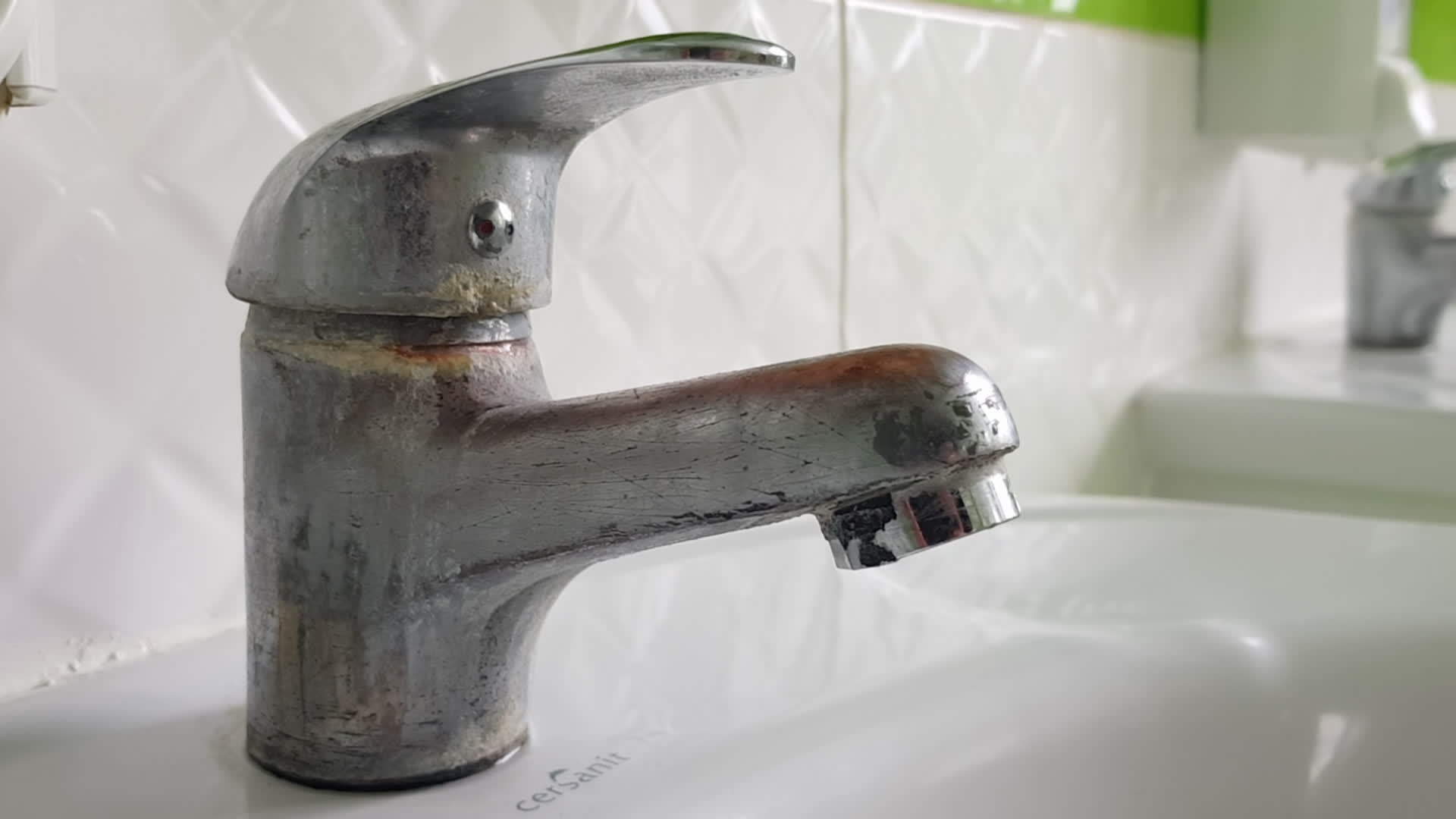 Old and dirty faucet and white ceramic sink. The concept of cleaning