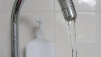 Nahaufnahme des Trinkens von Leitungswasser, das aus einem Wasserhahn fließt. Entwerfen einer Armatur in der Küche oder im Badezimmer. das konzept der wassereinsparung und des wasserverbrauchs, des tarifs und des wasserpreises.