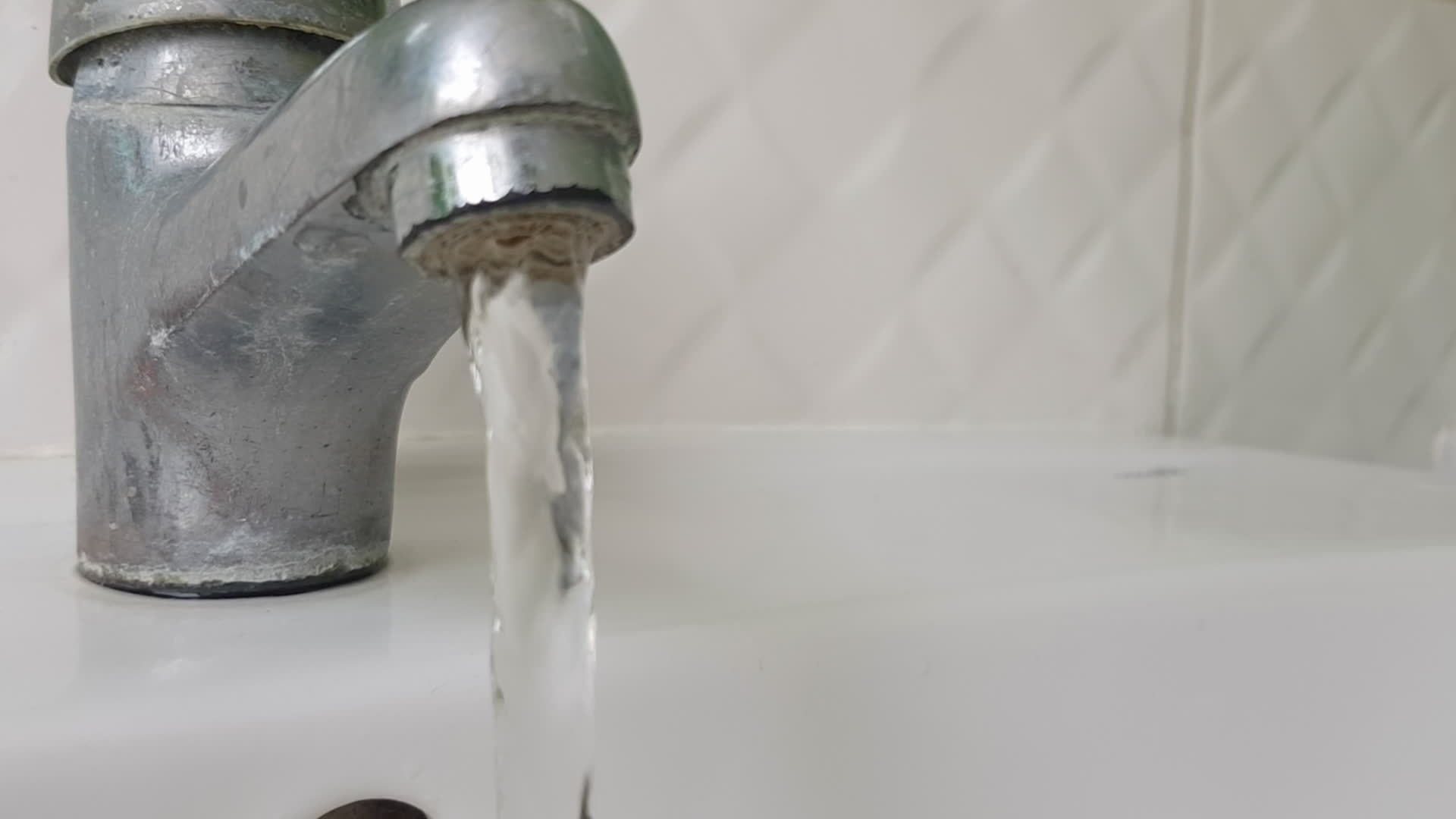 Old and dirty faucet and white ceramic sink. The concept of cleaning, repairing or replacing a