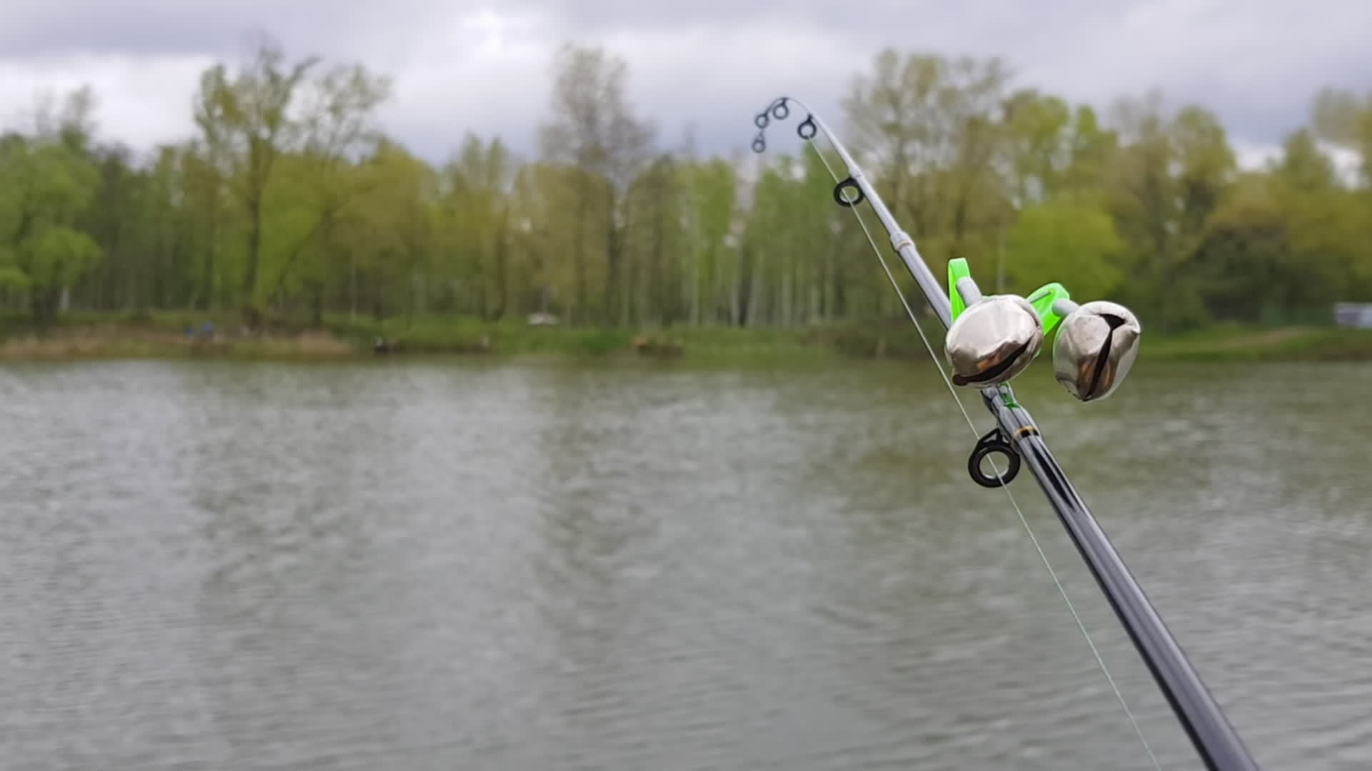 Silver fishing bells are worn on a fishing rod while fishing. Bite-call  signal, at the tip of the rod. A bite alarm will alert you to a bite.  Fishing tackle close-up. 11365671