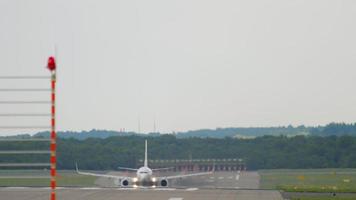 el avión comercial gana velocidad y despega, vista desde el final de la pista. avión vuela por encima video