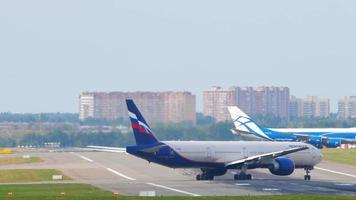 Moskou, Russisch federatie september 12, 2020 - aeroflot Russisch luchtvaartmaatschappijen boeing 777 passagiersvliegtuig binnengaan de landingsbaan voor nemen uit terwijl lucht brug lading boeing 747 vrachtvliegtuig weggaan de landingsbaan. video