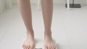 actividad de estilo de vida con la pierna de la mujer para medir la escala de peso para la dieta con los pies descalzos, primer plano de la medida de pérdida de peso delgada de la niña para el control de los alimentos y la nutrición. video