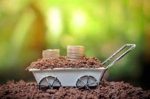 Stack of coins growing up on wheel barrow for business investment or saving concept photo
