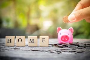 Business concept, hand putting coins in pink piggy bank for home photo