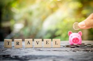 Business concept, hand putting coins in pink piggy bank for travel photo