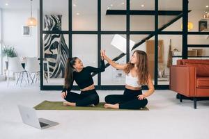 Two women while sitting in the lotus position give a high five photo