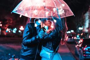 Guy and girl kissing under an umbrella photo