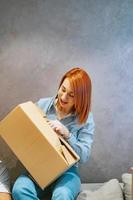 Young woman holding cardboard boxes and shakes it photo