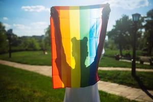Young woman holding an LGBT pride flag in her hands. photo