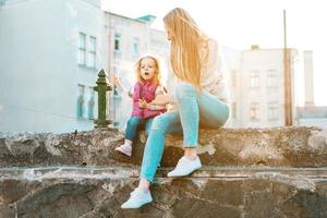 mamá e hija se sientan juntas en la cerca foto