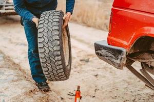 el hombre cambia la rueda manualmente en un camión todoterreno 4x4 foto