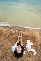 beautiful young girl sitting and holding a smartphone in her hands, top view photo