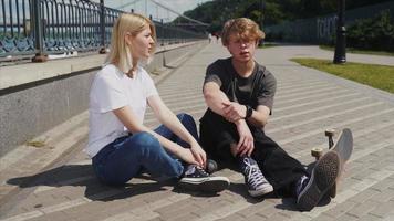 chico y chica están sentados en la calle y hablando foto