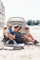 Couple sitting on the asphalt behind the car photo