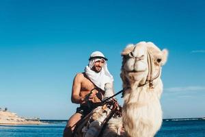 Guy rides on a camel on the beach photo