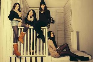 Four stylish models posing sitting on the fence. Christmas background photo