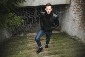 A man dressed in jeans and black jacket on autentic stairs photo