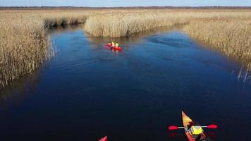 Group of people in kayaks among reeds on the autumn river. photo