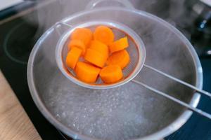 The image of a small amount of chopped carrots over a boiling pan photo