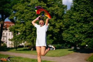 mujer joven ondeando la bandera del orgullo lgbt en el parque. foto