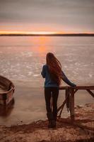 mujer disfrutando del tiempo relajándose junto al hermoso lago al amanecer. foto