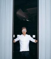 un chico guapo con gafas de sol abre la puerta del hangar. foto