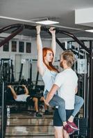 Guy ayuda a su novia a entrenar en el gimnasio. foto