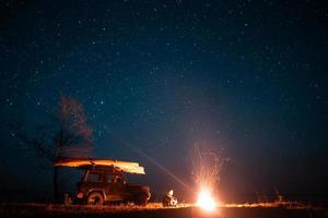 Happy man sitting in front burning bonfire photo