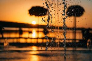 stream of a fountain splashes water, sunset photo