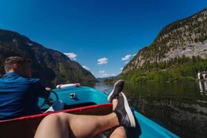 Handsome young guy controls a motorboat on a mountain lake photo