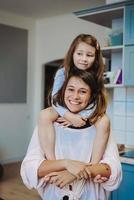 beautiful little daughter piggybacking on her happy mother photo