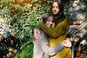 Two girls hugging in the shade of of leaves photo