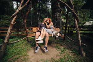 beautiful couple together with dog on a swing photo