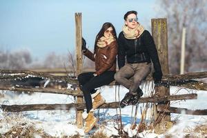 young couple sitting on old fence photo