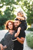 Happy parents with a small daughter sitting on the shoulders photo