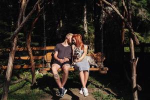 beautiful couple together with dog on a swing photo