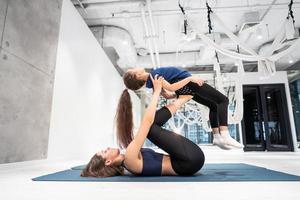 Young adult mother doing fitness with her little daughter photo