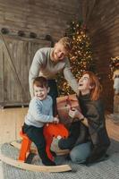 Young caucasian family mom dad son near fireplace christmas tree photo